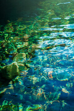 View of clear water with submerged stones and light refraction patterns in the United Kingdom.