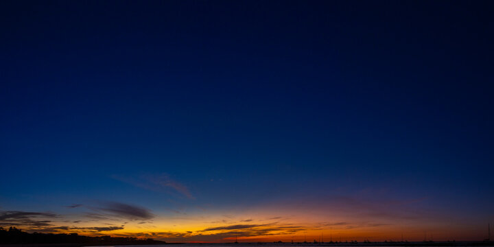 Minimalistic twilight bay with silhouettes of anchored sailboat fleets under a dark sky