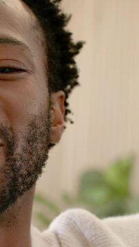 Vertical video: Laughing man in sweater at home reaching as cam shifting, covering lens, copy space