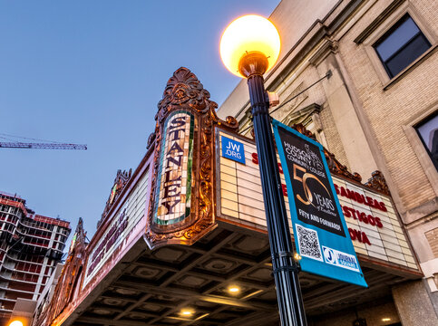 Jersey City, NJ - US - Oct 7, 2026 : The Stanley Theater marquee at Journal Square displays elaborate ornate metalwork, vertical lettering and illuminated signs beside a streetlamp and college banner.