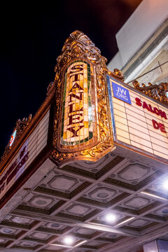 Jersey City, NJ - US - Oct 7, 2026 : A close view of the Stanley Theater's vertical stained glass sign shows ornate gilded scrollwork and the illuminated marquee above a patterned canopy after dusk.