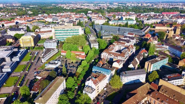 H&ocirc;tel d'Alsace stands beside the Ill near Petite France in Strasbourg, Grand Est, France, with dense urban buildings, Rue Humann and historic landmarks extending beyond, drone lateral slide.