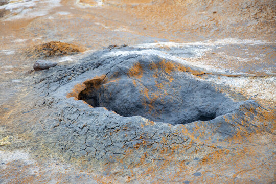 View of a bubbling mud pot at Hverir Sulfur Springs in the Namafjall geothermal area, featuring cracked earth and colorful mineral deposits in Reykjahlid, Thingeyjarsveit, Iceland.