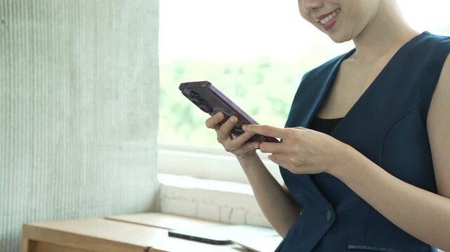 Smiling woman in dark business clothing uses a smartphone beside a bri