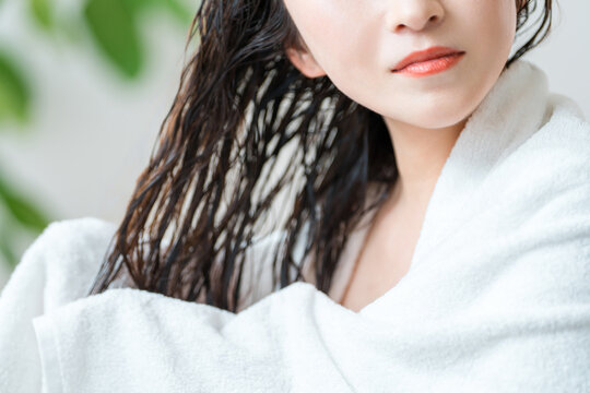 A woman towel-drying her wet hair. Hair care image after bathing