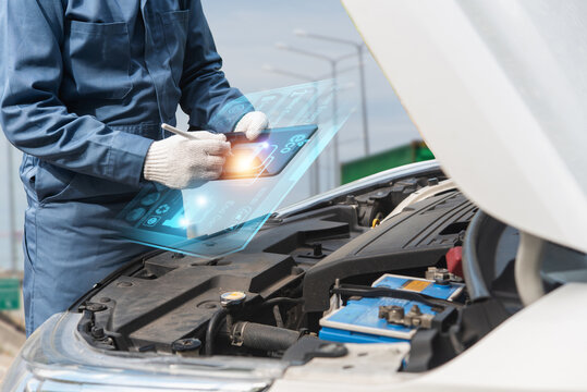 Auto technician inspecting car engine with digital tablet displaying futuristic holographic diagnostic interface. Smart vehicle maintenance concept. Human-created, not AI.