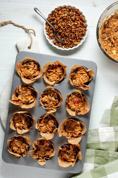 A muffin tin filled with morning glory muffin batter ready to add candied pecans