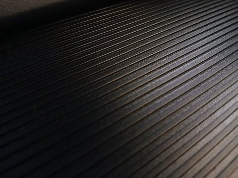 Dark ribbed textured background with diagonal parallel grooved lines and gradient lighting