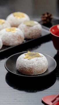金箔の紅葉を飾った粉雪のような白い和菓子と黒い和食器