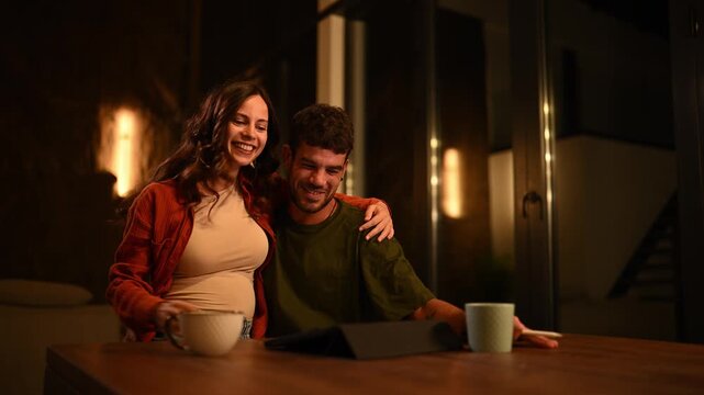 Joyful pregnant couple showing positive pregnancy test during a video call on a tablet at home