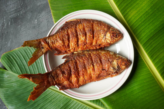 fried fish on a plate with banana lef as a backdrop