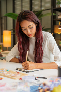Asian business owner handcrafted jelvery taking note order