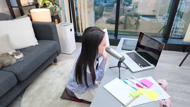 Asian Woman Recording Podcast and Working Online on Laptop at Home