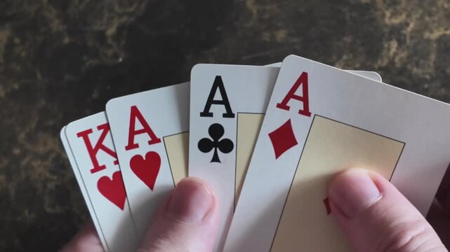 Close view following a hand and a combination of aces and kings moving across the table.