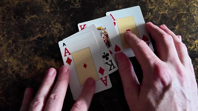 Playing cards grouped together by hand in slow motion with a detailed macro view on a gaming table.