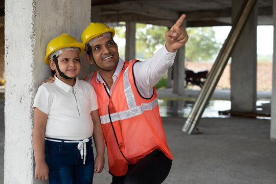 Indian little girl visits construction site. Engineer manager working with her like team and reviewing and analyzing the work in progress. The little girl takes the tour of builder construction