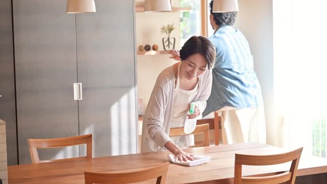 自宅のダイニングで大掃除や家事を協力して行う日本人夫婦、共働き家庭の家事分担と家事シェア、テーブルや窓の拭き掃除をする男女の快適なライフスタイルイメージの動画