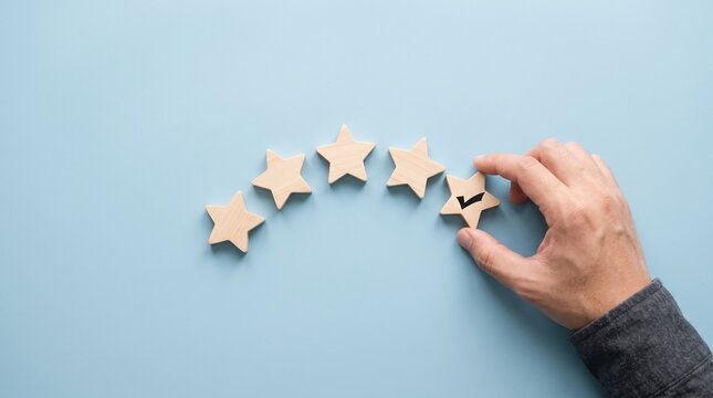 Person Hand Carefully Placing A Wooden Star Block To Complete A Five Star Rating System For Customer Service Satisfaction