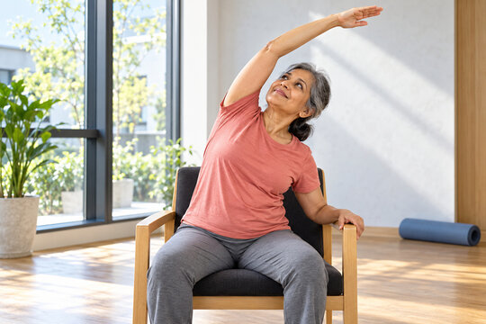 Older woman performs a seated side stretch in a studio