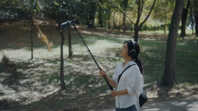 Young Asian Woman Wearing Headphones Listening to Nature Sounds in Park