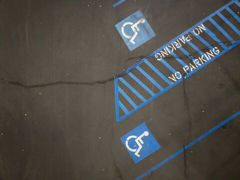 Disability parking zone with worn blue paint on pavement