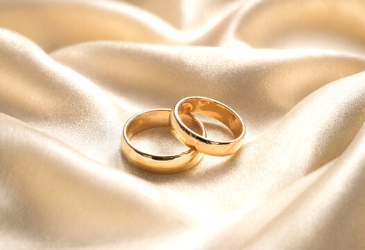 Two Gold Wedding Rings Placed on Soft Light Beige Fabric