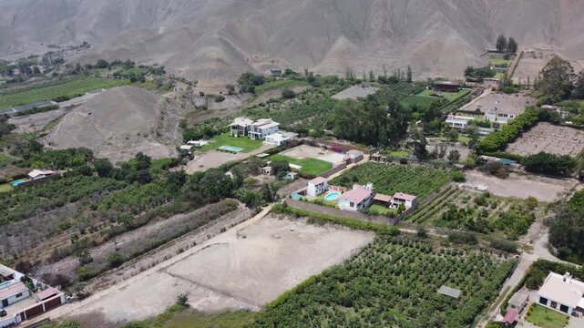 High angle drone footage showing agricultural fields and villas in a dry, mountainous peruvian