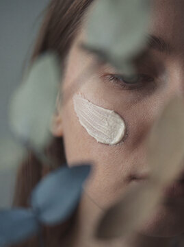 Close-up of woman's face with skincare cream swatch on cheek