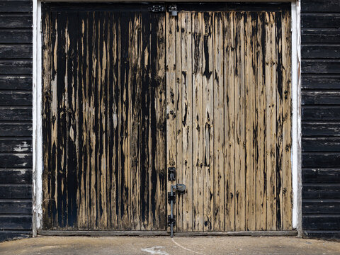 Background texture of old wooden garage doors with peeling black paint