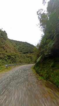 Driving down the dangerous gravel curves of Death Road surrounded by tropical vegetation in Bolivia