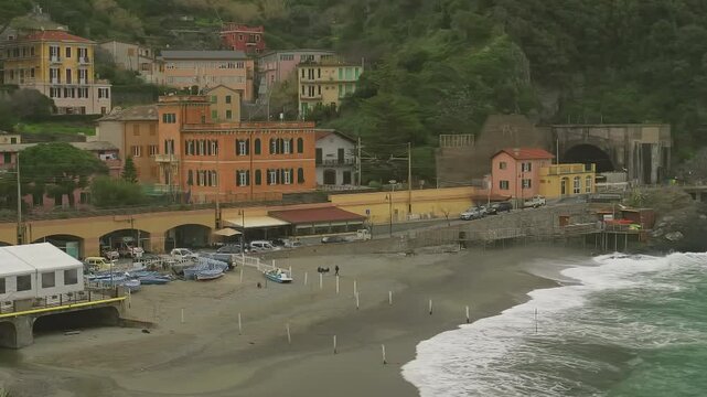 Waves on Sandy Beach Near Railway Tunnel and Hillside Buildings in Monterosso, Italy