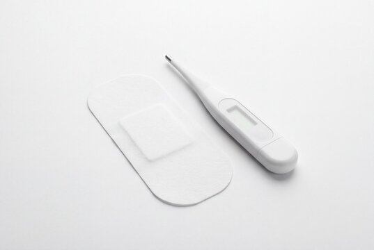 White Medical Patch and Digital Thermometer on White Background