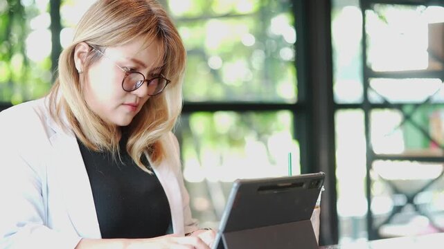 Focused Professional Woman Using Tablet at Cafe Workspace