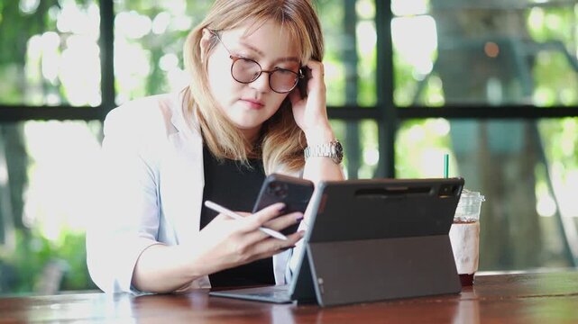 Thoughtful Businesswoman Using Tablet and Stylus at Cafe