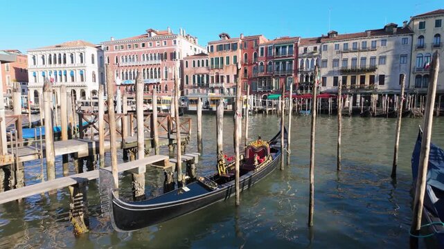 Traditional Venetian gondola moored beside wooden canal piers