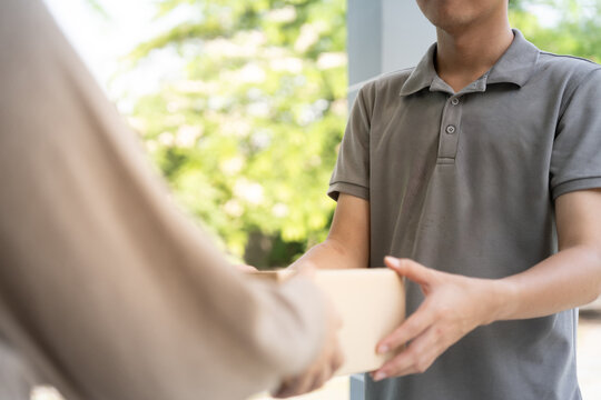 Happy smiling woman receives boxes parcel from courier in front house. Delivery man send deliver express. online shopping, paper containers, takeaway, postman, delivery service, packages