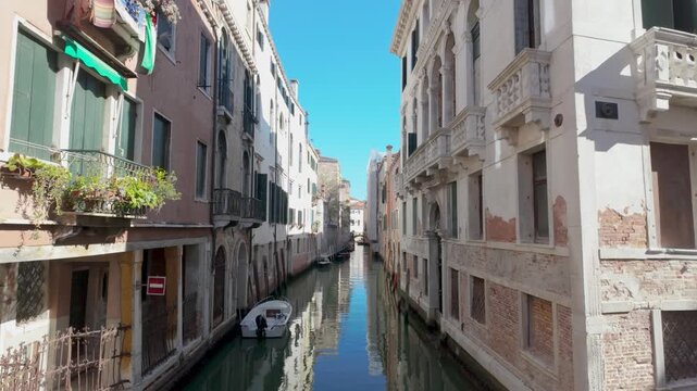 Narrow historic canal lined by weathered palazzi balconies