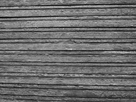 monochrome textured surface consisting of multiple narrow, horizontal brown wooden slats or panels arranged tightly parallel to each other, displaying a weathered natural grain pattern
