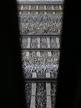 a natural black frame that frames the view of several parallel railroad tracks, whose concrete ties are laid on a bed of crushed gray ballast