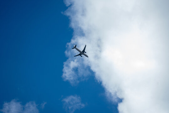 airplane flying through white clouds in blue sky