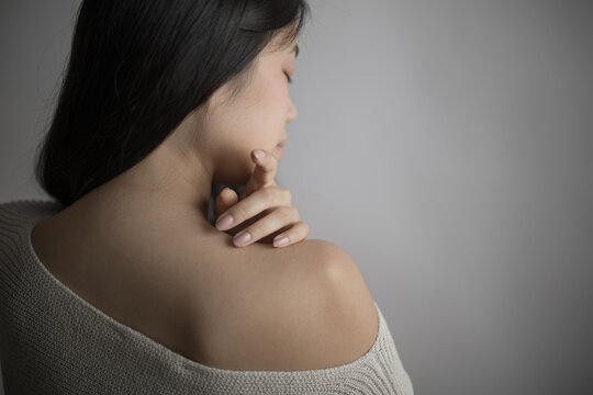 Southeast Asian woman touching shoulder in a thoughtful, peaceful pose