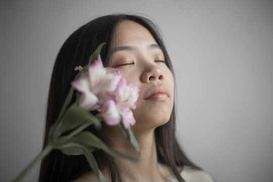Portrait of Southeast Asian woman with closed eyes holding pink