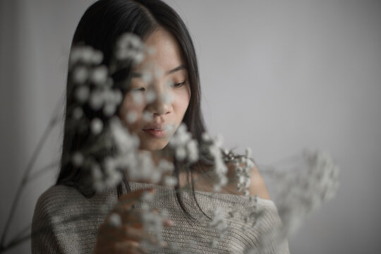Emotional Southeast Asian woman touching delicate baby's breath