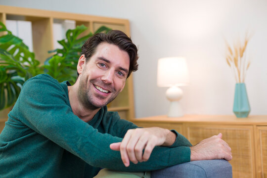 White man smiling and relaxing in a cozy living room setting