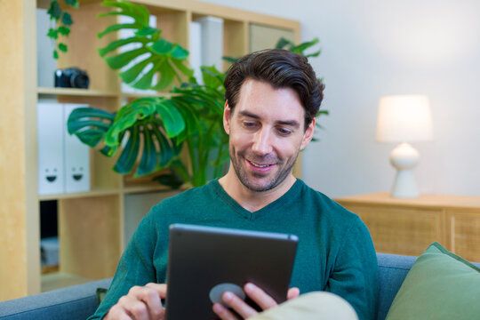 Young white man using tablet in modern living room