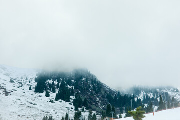Fototapeta premium Snow-covered mountain terrain obscured by dense fog