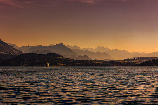 The Swiss lake Zugersee (Zug Lake) with the alps mountain layer in the distance  at the sunset  golden hour time