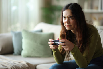 Frustrated young woman playing video game at home © Antonioguillem