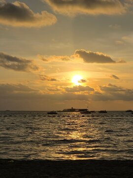 Golden Sunset Over the Ocean with Dramatic Clouds and Sunlight Reflection
