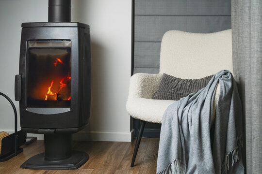 Comfort from a warm fire in a cozy space with a chair and a soft blanket nearby